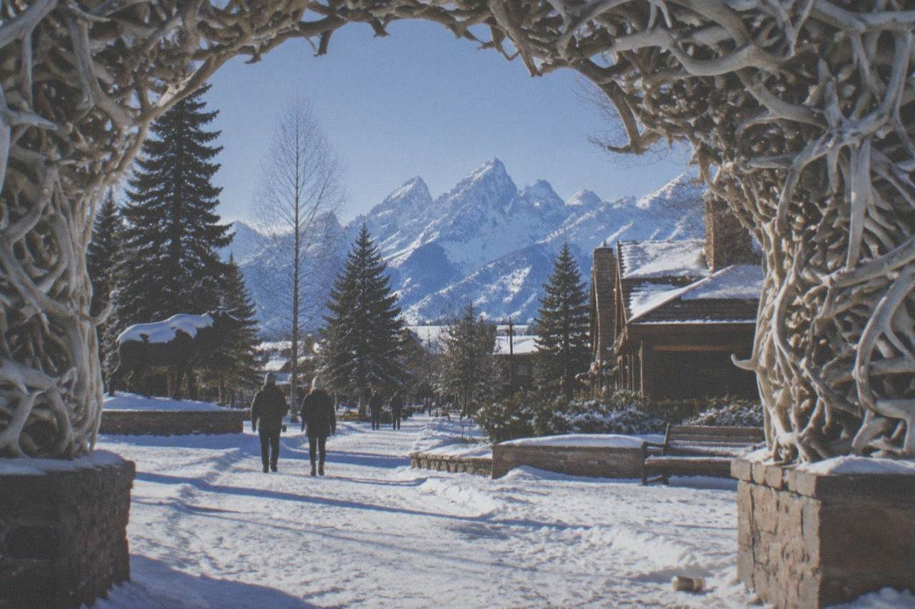 Snow-covered western town square framed by mountain peaks under a clear winter sky