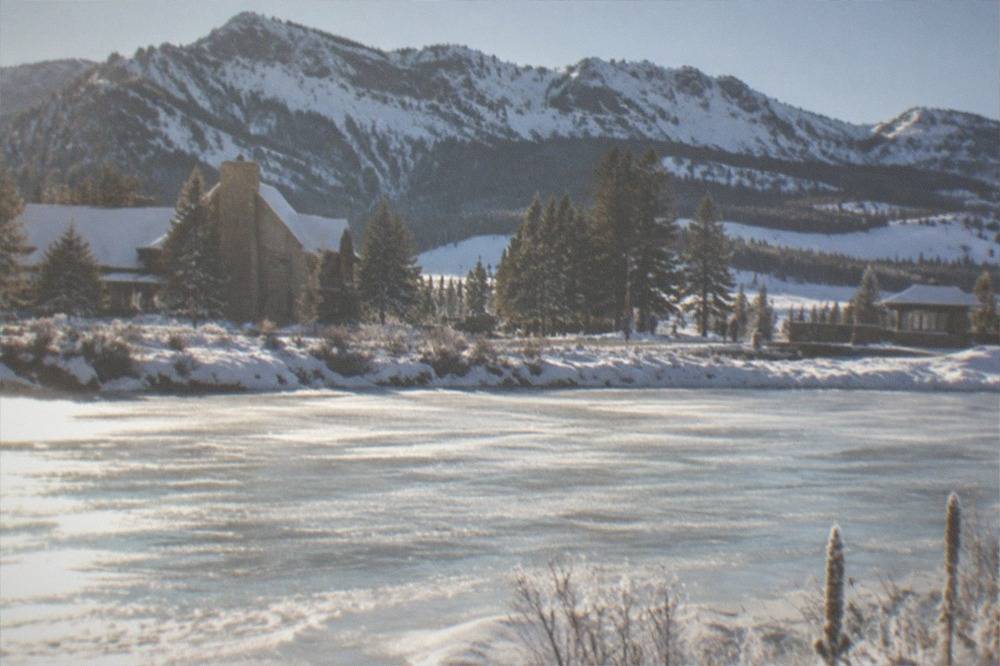 Frozen river winding through a snowy valley with mountains under a bright cold sky