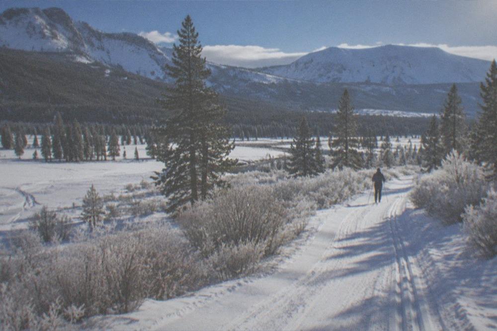 Fresh snow blanketing a wide mountain valley with a groomed trail cutting through the middle