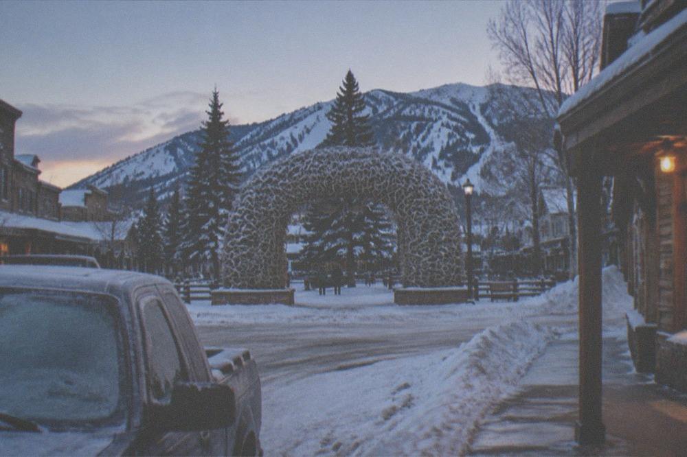 A winter gateway town street with snow banks and a clear cold evening sky