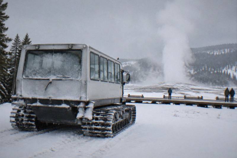 Snowcoach vehicle at Old Faithful basin on a guided winter tour from Jackson Hole